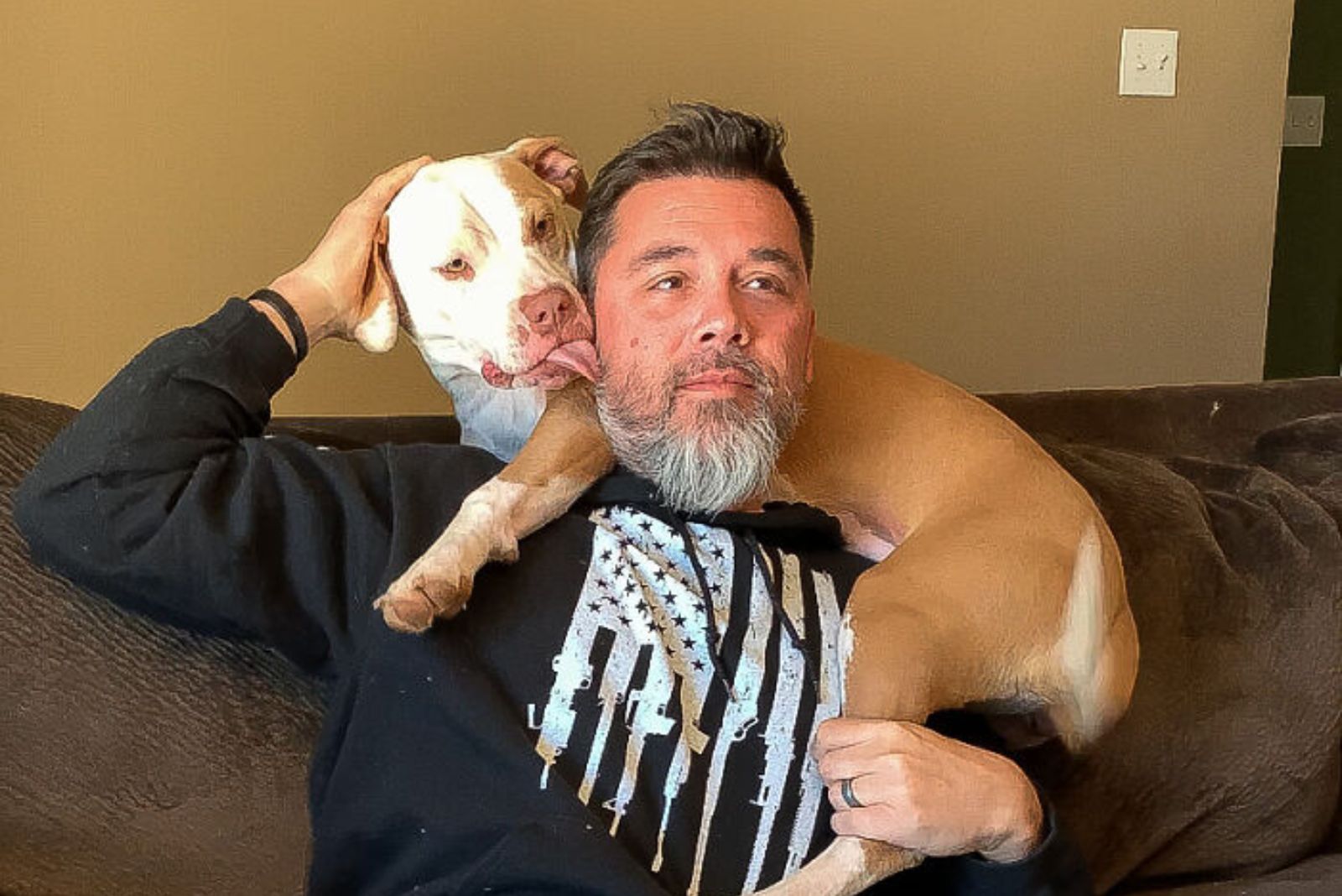 grown pitbull lying on man's shoulder