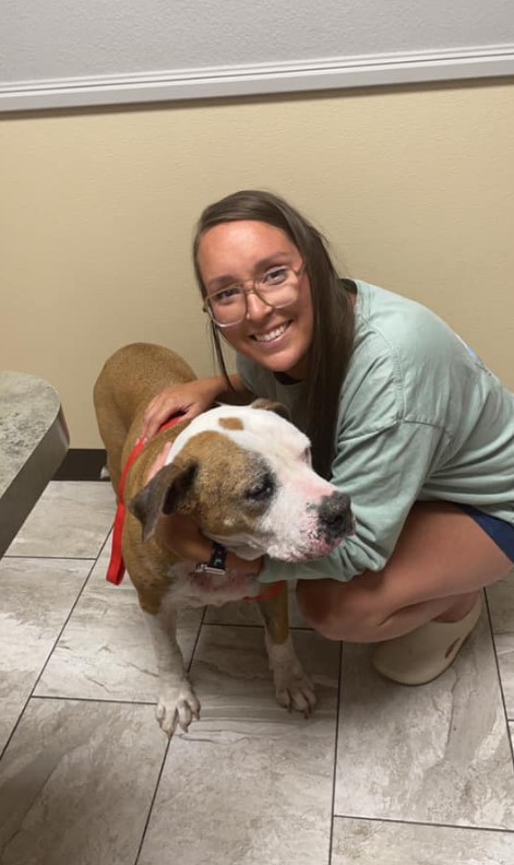 smiling woman with glasses hugs dog